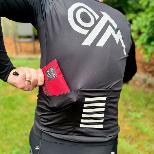 Gravel biker placing The Grindy XC & Gravel First Aid Kit into his back jersey pocket | Cascade First Aid
