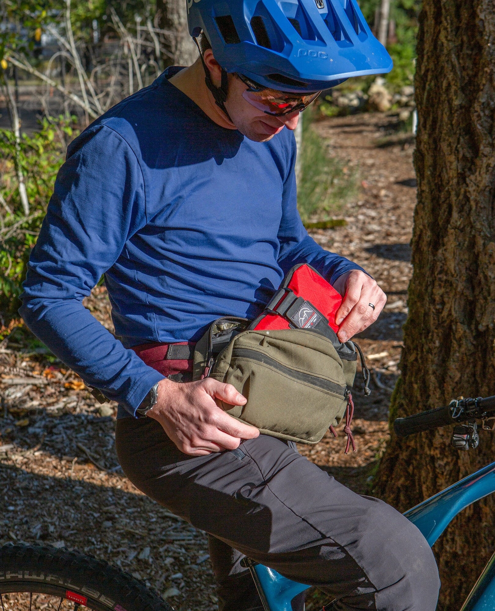 Mountain biker placing the Galby Mountain Biking First Aid kit inside his hip pack for another enduro or downhill lap | Cascade First Aid